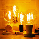 Three illuminated light bulbs on wooden bases with a warm glow