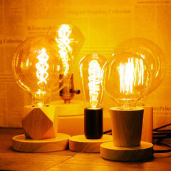 Three illuminated light bulbs on wooden bases with a warm glow