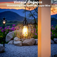 Decorative outdoor light with shimmering gold beads and copper wire in a garden setting.