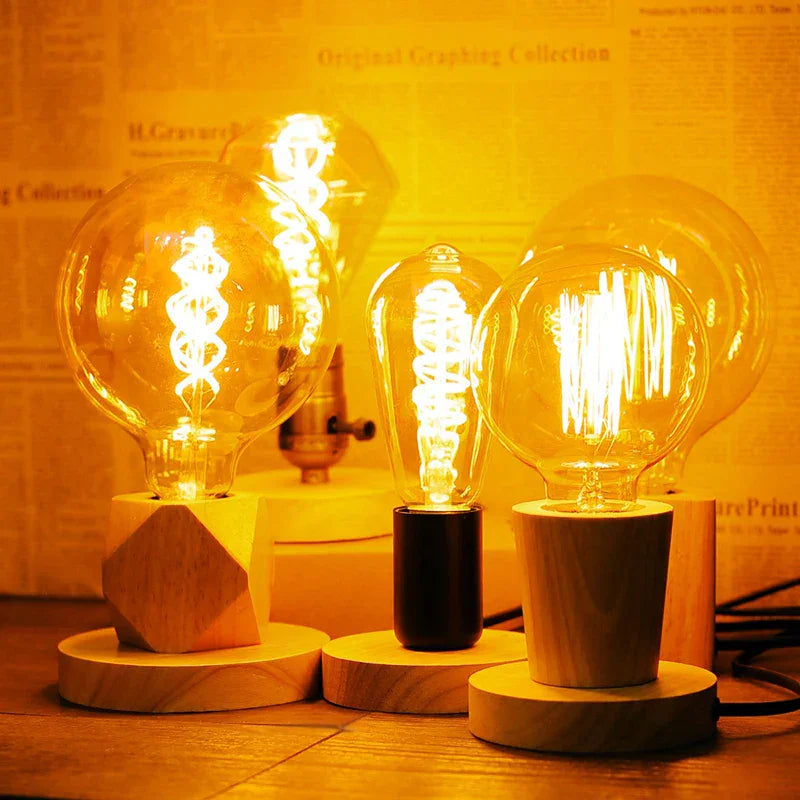 Three illuminated light bulbs on wooden bases with a warm glow 