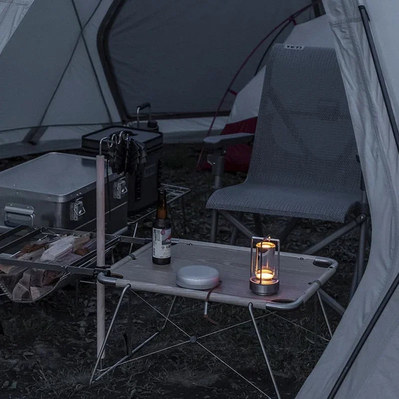Camping scene with a table by a fire near a body of water at night.